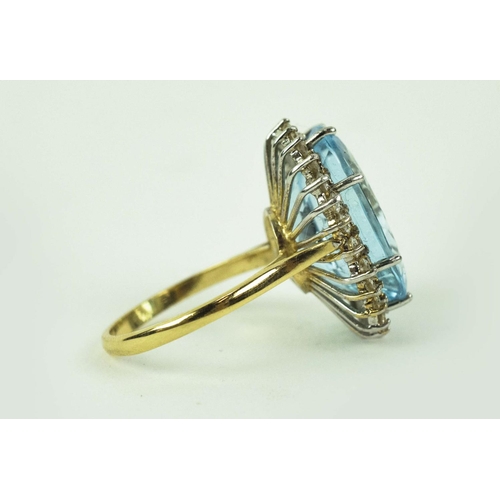 27 - AN 18CT YELLOW GOLD TOPAZ AND DIAMOND DRESS RING, the oval blue topaz of approximately 10 carats, su... 