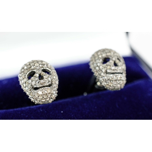 31 - A PAIR OF SKULL SHAPED CUFFLINKS, white metal and set with diamonds, complete with box