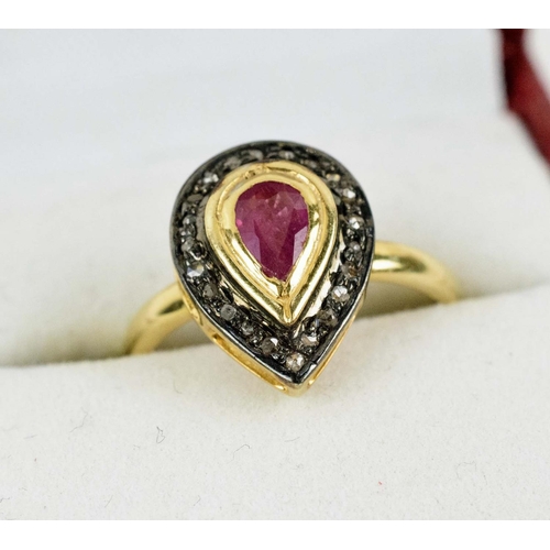 34 - A RUBY AND DIAMOND DRESS RING, the central pear cut ruby surrounded by rose cut diamonds, in a silve... 