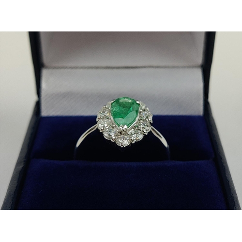 18 - A PLATINUM EMERALD AND DIAMOND DRESS RING, the pear shaped emerald surrounded by a border of ten dia... 