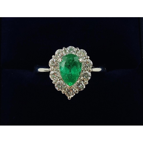 18 - A PLATINUM EMERALD AND DIAMOND DRESS RING, the pear shaped emerald surrounded by a border of ten dia... 