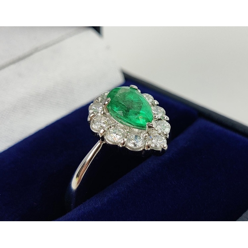 18 - A PLATINUM EMERALD AND DIAMOND DRESS RING, the pear shaped emerald surrounded by a border of ten dia... 