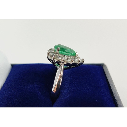 18 - A PLATINUM EMERALD AND DIAMOND DRESS RING, the pear shaped emerald surrounded by a border of ten dia... 