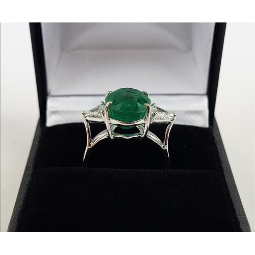 24 - AN 18CT WHITE GOLD EMERALD AND DIAMOND RING, the central oval cut emerald flanked by trilliant cut d... 