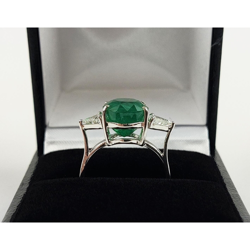 24 - AN 18CT WHITE GOLD EMERALD AND DIAMOND RING, the central oval cut emerald flanked by trilliant cut d... 