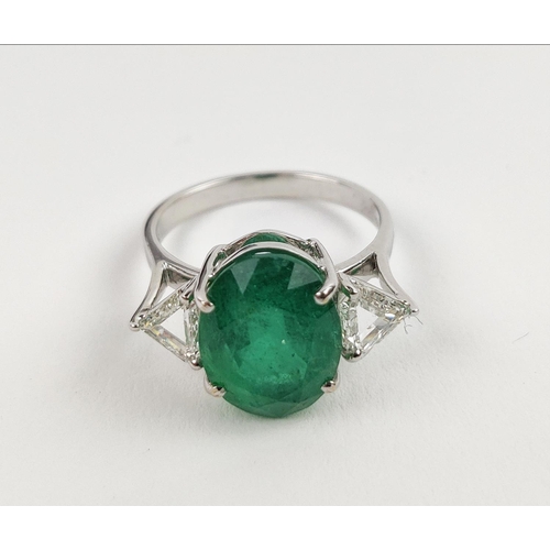 24 - AN 18CT WHITE GOLD EMERALD AND DIAMOND RING, the central oval cut emerald flanked by trilliant cut d... 