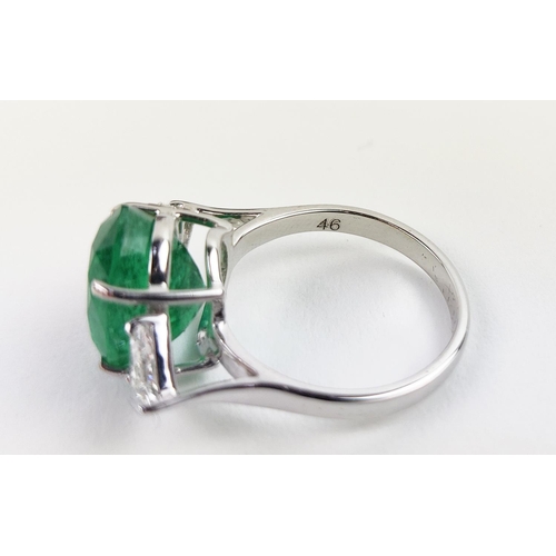 24 - AN 18CT WHITE GOLD EMERALD AND DIAMOND RING, the central oval cut emerald flanked by trilliant cut d... 