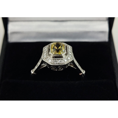 27 - A PLATINUM YELLOW SAPPHIRE AND DIAMOND SET RING, the central mixed cut stone surrounded by a halo of... 