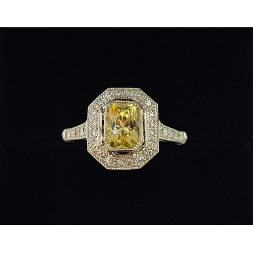 27 - A PLATINUM YELLOW SAPPHIRE AND DIAMOND SET RING, the central mixed cut stone surrounded by a halo of... 