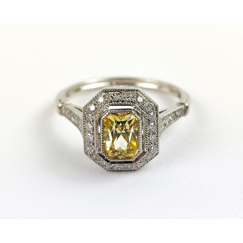 27 - A PLATINUM YELLOW SAPPHIRE AND DIAMOND SET RING, the central mixed cut stone surrounded by a halo of... 