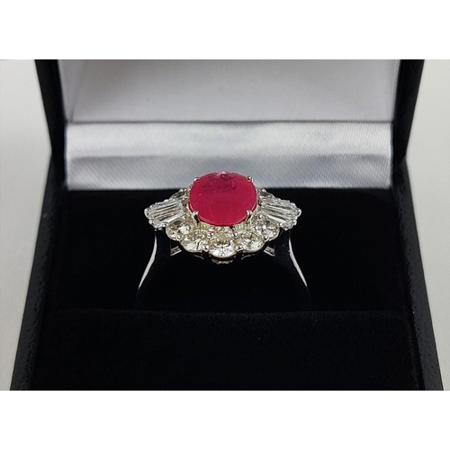 28 - A 18CT WHITE GOLD RUBY AND DIAMOND RING, the oval mixed cut ruby surrounded by a halo of round brill... 