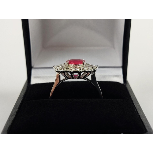 28 - A 18CT WHITE GOLD RUBY AND DIAMOND RING, the oval mixed cut ruby surrounded by a halo of round brill... 