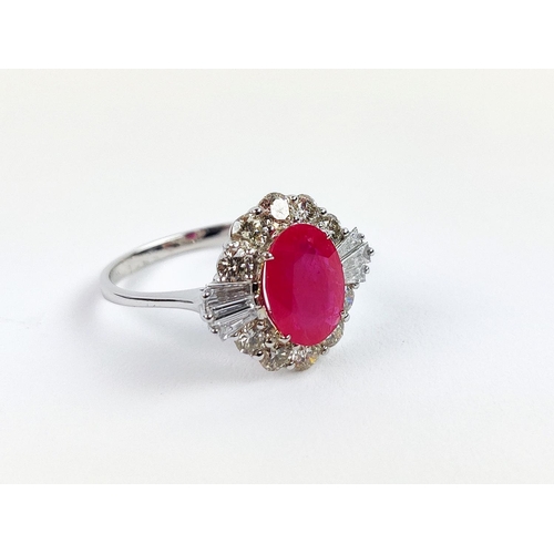 28 - A 18CT WHITE GOLD RUBY AND DIAMOND RING, the oval mixed cut ruby surrounded by a halo of round brill... 