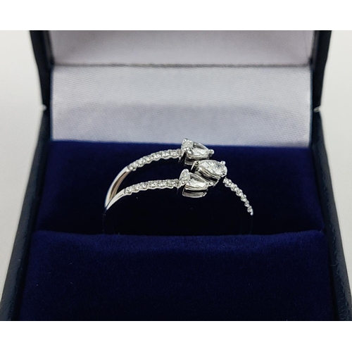 35 - A 9CT WHITE GOLD DIAMOND RING, with three main pear shaped diamonds, diamond set shoulders, total di... 