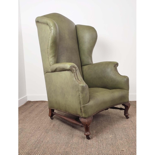 396 - WING ARMCHAIR, Victorian mahogany in green leather on steel castors, 132cm H x 79cm W x 95cm D.