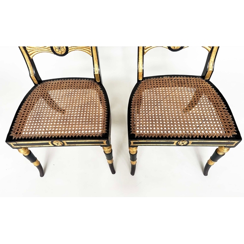 194 - REGENCY SIDE CHAIRS, a pair, ebonised and parcel gilt each with hand painted bow back rail and cane ... 