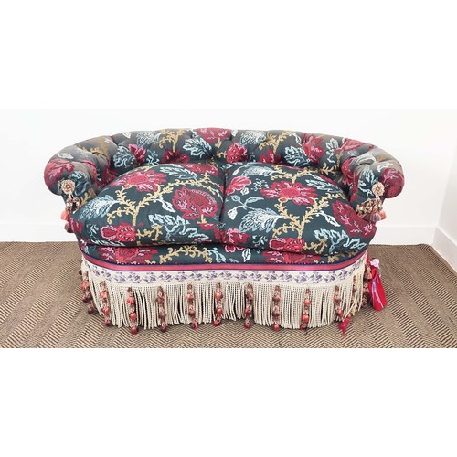 367 - SOFA, of curved form, with a button back, in a polychrome woven fabric with extensive swags and tass... 