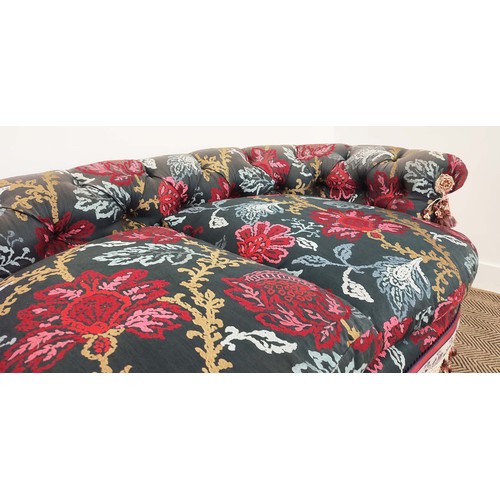 367 - SOFA, of curved form, with a button back, in a polychrome woven fabric with extensive swags and tass... 