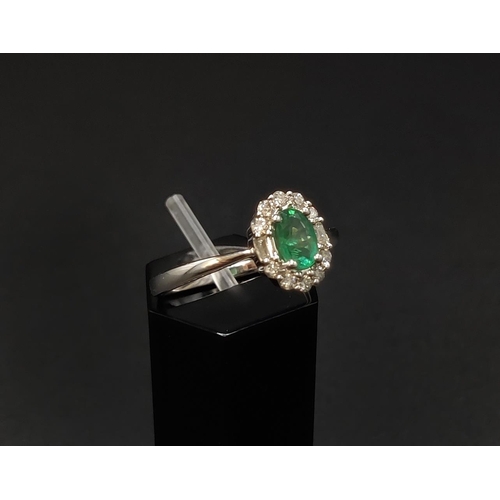 32 - AN 18CT WHITE GOLD EMERALD AND DIAMOND RING, the central oval cut emerald of approximately 0.45 cara... 