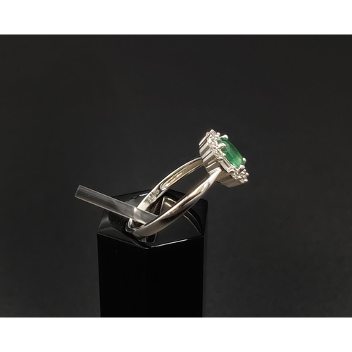 32 - AN 18CT WHITE GOLD EMERALD AND DIAMOND RING, the central oval cut emerald of approximately 0.45 cara... 