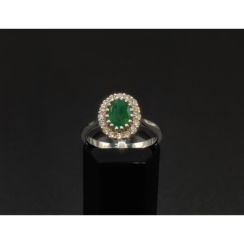 39 - AN 18CT WHITE GOLD EMERALD AND DIAMOND CLUSTER RING, the central oval cut emerald of approximately 1... 