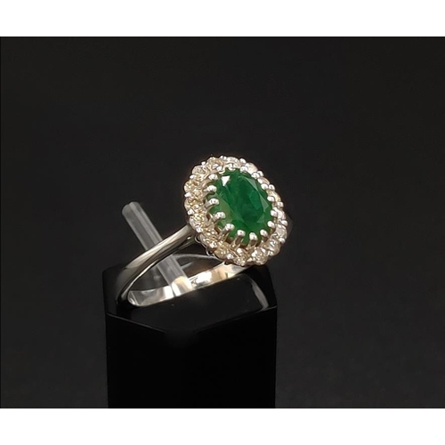 39 - AN 18CT WHITE GOLD EMERALD AND DIAMOND CLUSTER RING, the central oval cut emerald of approximately 1... 