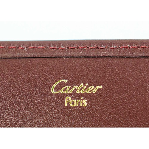 20 - A CARTIER BURGUNDY LEATHER LADIES PURSE, gilt metal mounts, with multiple sections, complete with or... 