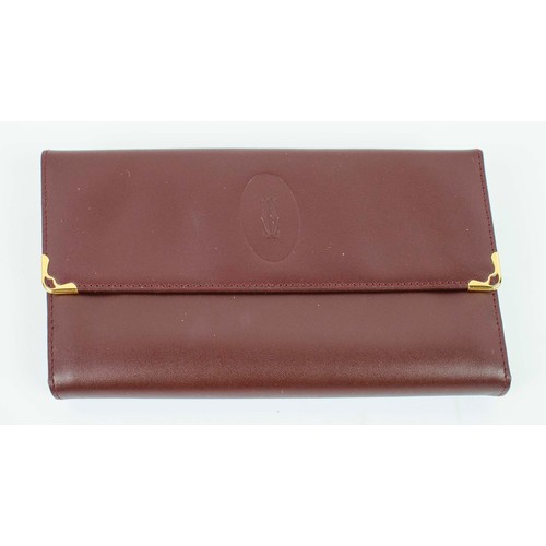 20 - A CARTIER BURGUNDY LEATHER LADIES PURSE, gilt metal mounts, with multiple sections, complete with or... 