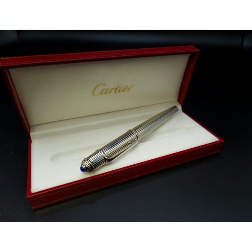 63 - A CARTIER STAINLESS STEEL FOUNTAIN PEN, with an 18ct white gold nib, blue resin cabochon to cap term... 