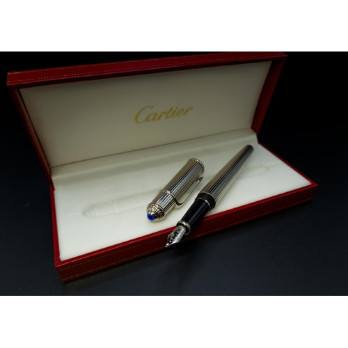 63 - A CARTIER STAINLESS STEEL FOUNTAIN PEN, with an 18ct white gold nib, blue resin cabochon to cap term... 