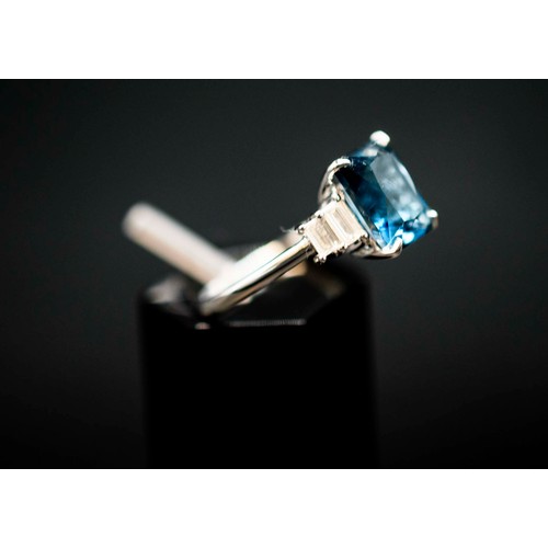 48 - PLATINUM TOPAZ AND DIAMOND RING, the central London blue topaz flanked by baguette cut diamonds, the... 