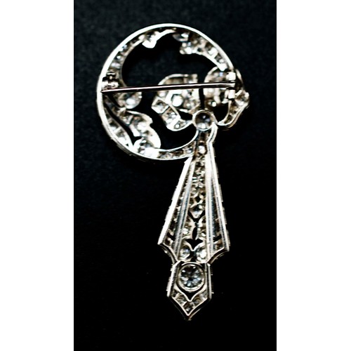 61 - ART DECO WHITE METAL AND DIAMOND ENCRUSTED BROOCH, circa 1925, in the form of a ribbon and bow, the ... 