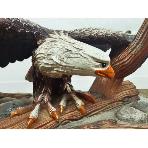 361 - LOW TABLE, shaped bevelled glass top on polychrome resin eagle support, 42cm H x 135cm W x 66cm D.