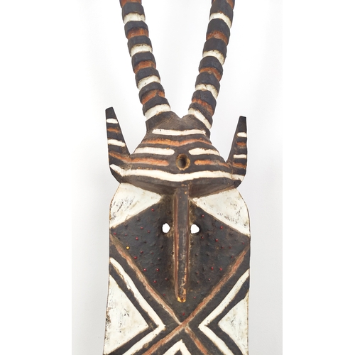 403 - AFRICAN MASK, carved wood on a metal floor stand, overall 203cm tall.