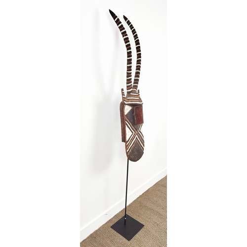 403 - AFRICAN MASK, carved wood on a metal floor stand, overall 203cm tall.