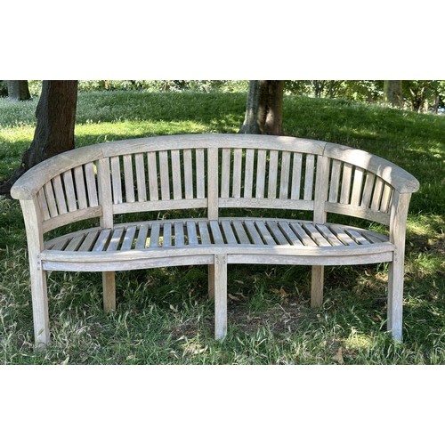 521 - BANANA GARDEN BENCH, well weathered teak of slatted construction with rounded back and arms, 158cm W... 