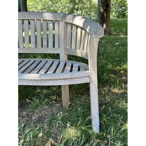 521 - BANANA GARDEN BENCH, well weathered teak of slatted construction with rounded back and arms, 158cm W... 