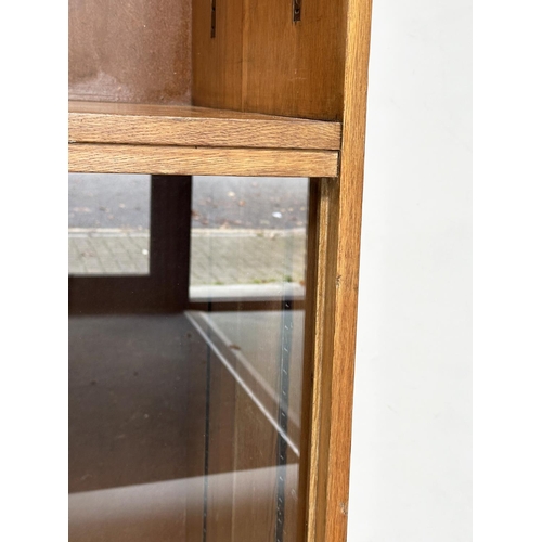 163 - DISPLAY CASE/BOOKCASE, mid 20th century oak with two adjustable glass shelves above a two sliding do... 