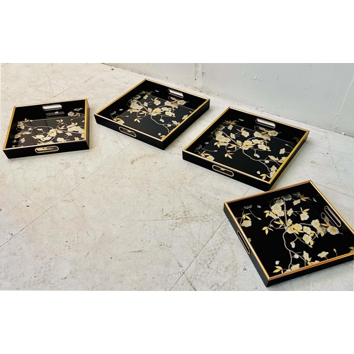 427 - DRINKS TRAYS, a set of four, black and gilt floral decoration, larger 5cm H x 40cm W x 40cm D and sm... 