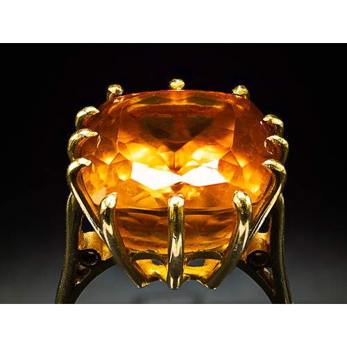 129 - A 18CT YELLOW GOLD AND ORANGE STONE DRESS RING, the large orange mixed cut stone possibly a spinel, ... 