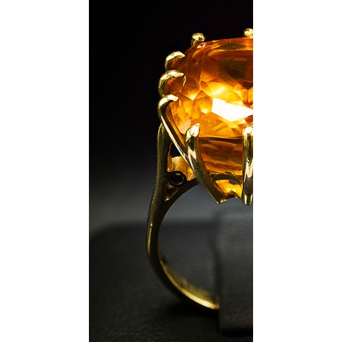 129 - A 18CT YELLOW GOLD AND ORANGE STONE DRESS RING, the large orange mixed cut stone possibly a spinel, ... 