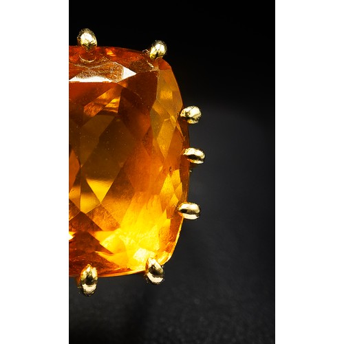 129 - A 18CT YELLOW GOLD AND ORANGE STONE DRESS RING, the large orange mixed cut stone possibly a spinel, ... 