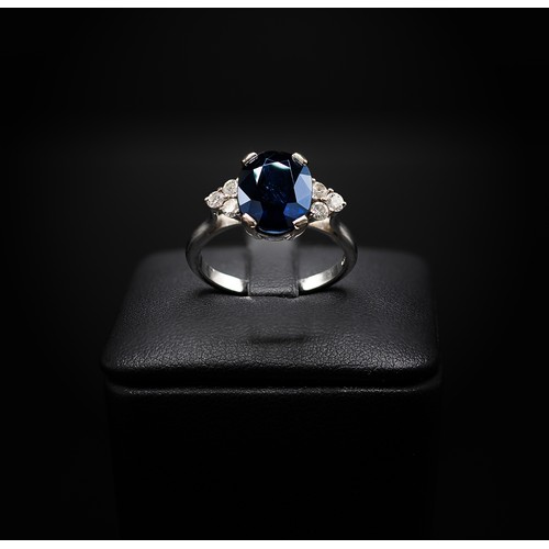 132 - AN 18CT WHITE GOLD SAPPHIRE AND DIAMOND RING, the large oval mixed cut sapphire flanked by six round... 