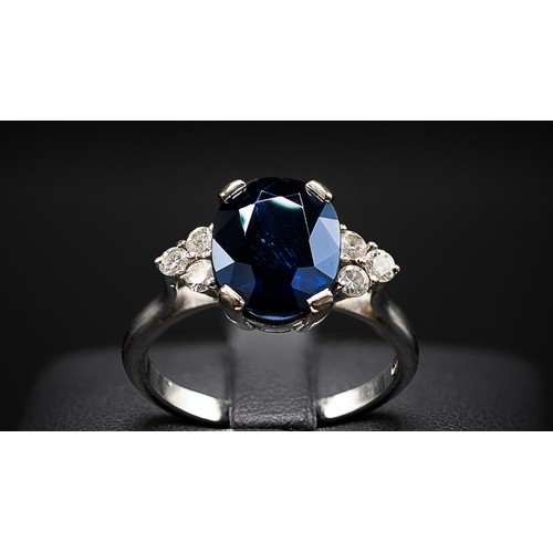 132 - AN 18CT WHITE GOLD SAPPHIRE AND DIAMOND RING, the large oval mixed cut sapphire flanked by six round... 