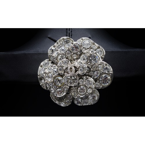 17A - CHANEL BROOCH, iconic camellia flower with a central double CC logo, rhinestones and silver tone met... 