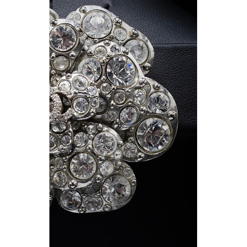 17A - CHANEL BROOCH, iconic camellia flower with a central double CC logo, rhinestones and silver tone met... 