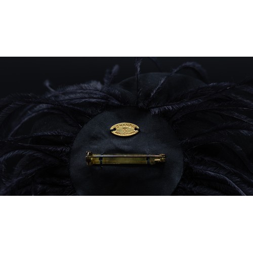 46 - CHANEL BROOCH, iconic black silk camellia with raw hem, ostrich feather at base, gold tone safety pi... 