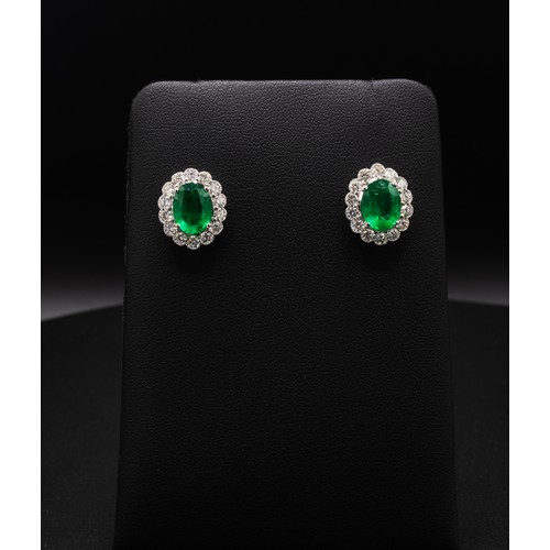 112 - A PAIR OF 18CT WHITE GOLD EMERALD AND DIAMOND STUD EARRINGS, each set with an oval mixed cut emerald... 