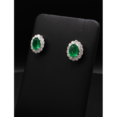 112 - A PAIR OF 18CT WHITE GOLD EMERALD AND DIAMOND STUD EARRINGS, each set with an oval mixed cut emerald... 