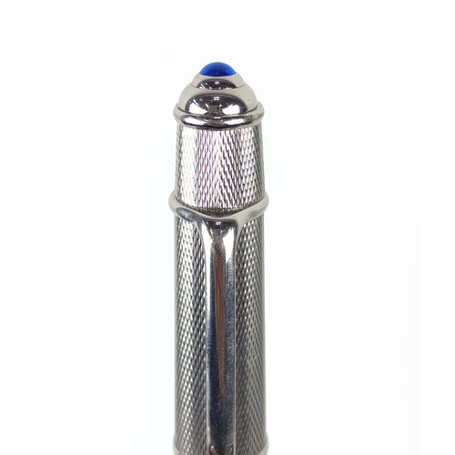 120A - TWO CARTIER BALLPOINT WHITE METAL PENS, comprising one with an engine turned case, blue cabochon ter... 